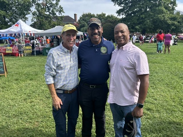 Mike Ramone posing with two men at the festival, with Dover’s Legislative Hall in the background.