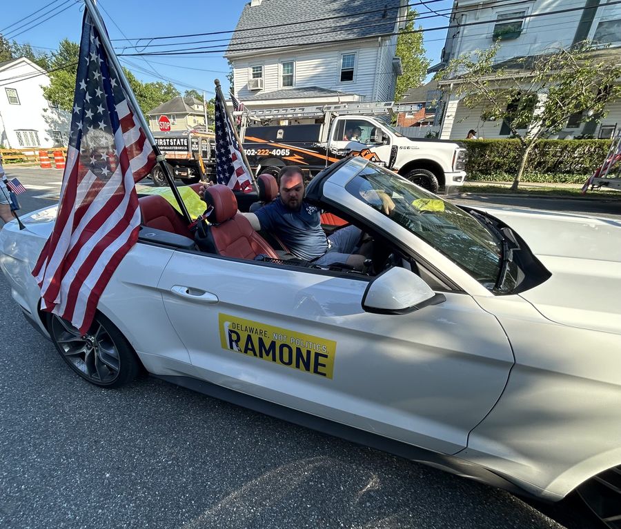 A white convertible carrying American flags and a Ramone: Delaware, Not Politics sign in the Dover parade.